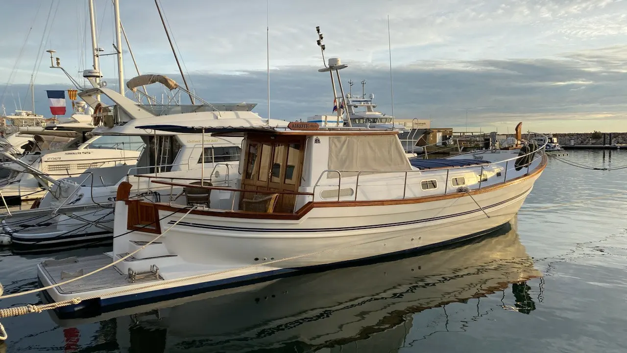 Menorquin 160 My — Bateau à moteur blanc amarré dans un port, photographié de trois quarts bâbord.