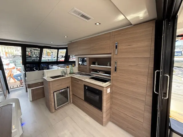 Aventura Catamarans Aventura 38 — Vue de la cuisine aménagée avec réfrigérateur, four et rangements en bois.