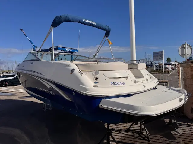 Chaparral 246 SSi WT — Bateau à moteur blanc et bleu photographié à terre, vu de trois quarts arrière.