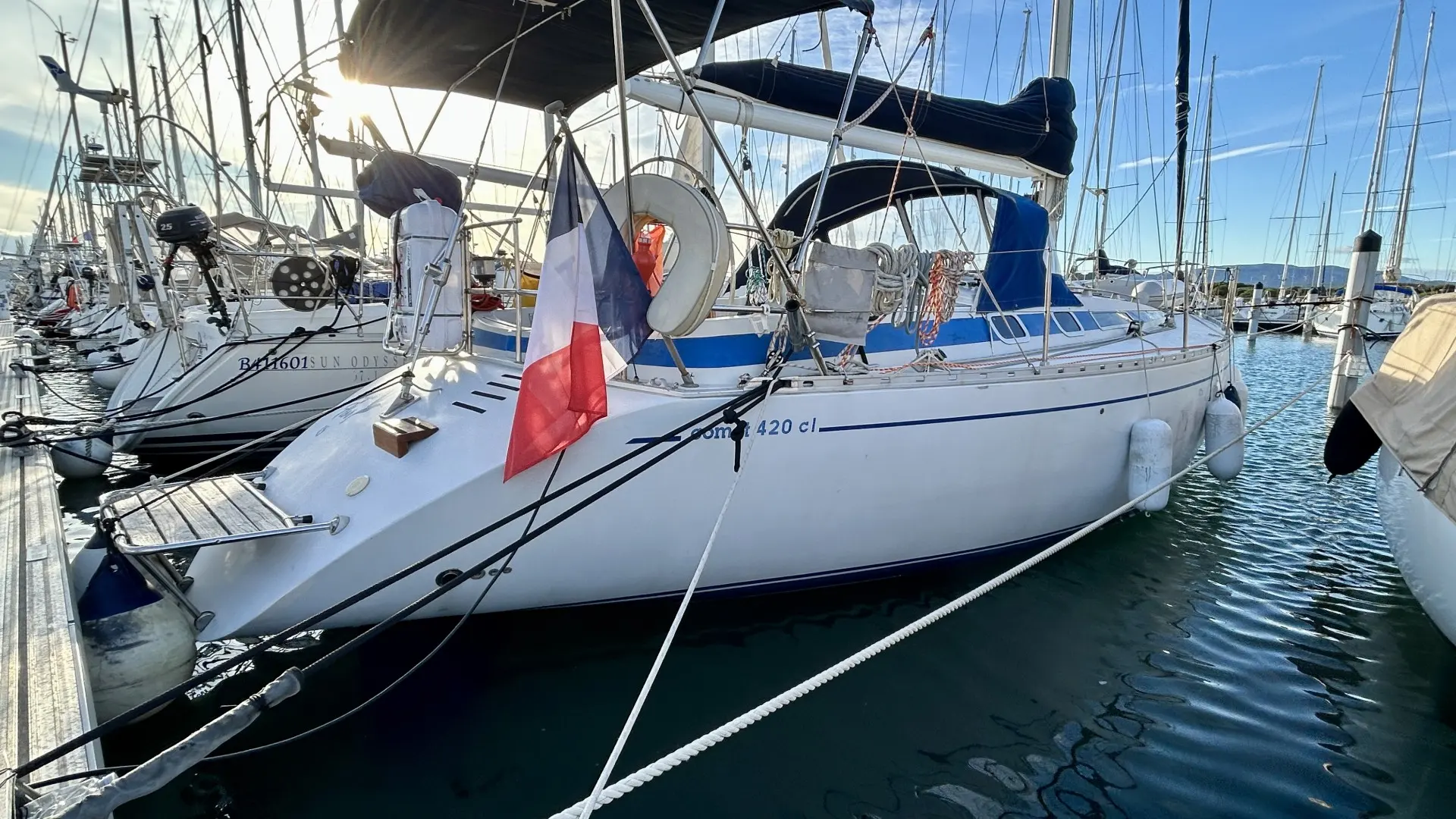 Comar Yachts COMET 420 — Vue trois-quarts d’un voilier blanc amarré dans une marina, sous un ciel dégagé.