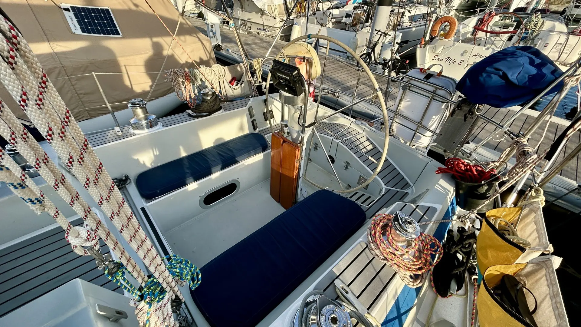 Comar Yachts COMET 420 — Vue du cockpit d'un voilier, avec barre à roue, winchs et manœuvres.