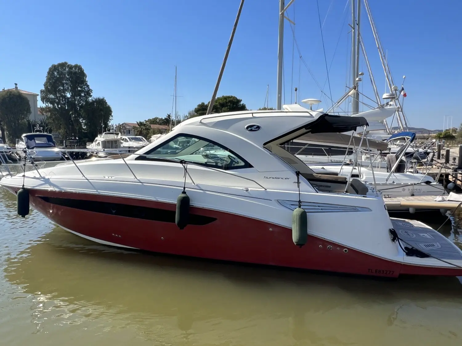Sea Ray 355 Sundancer — Bateau à moteur blanc et rouge amarré dans une marina, vu de profil.