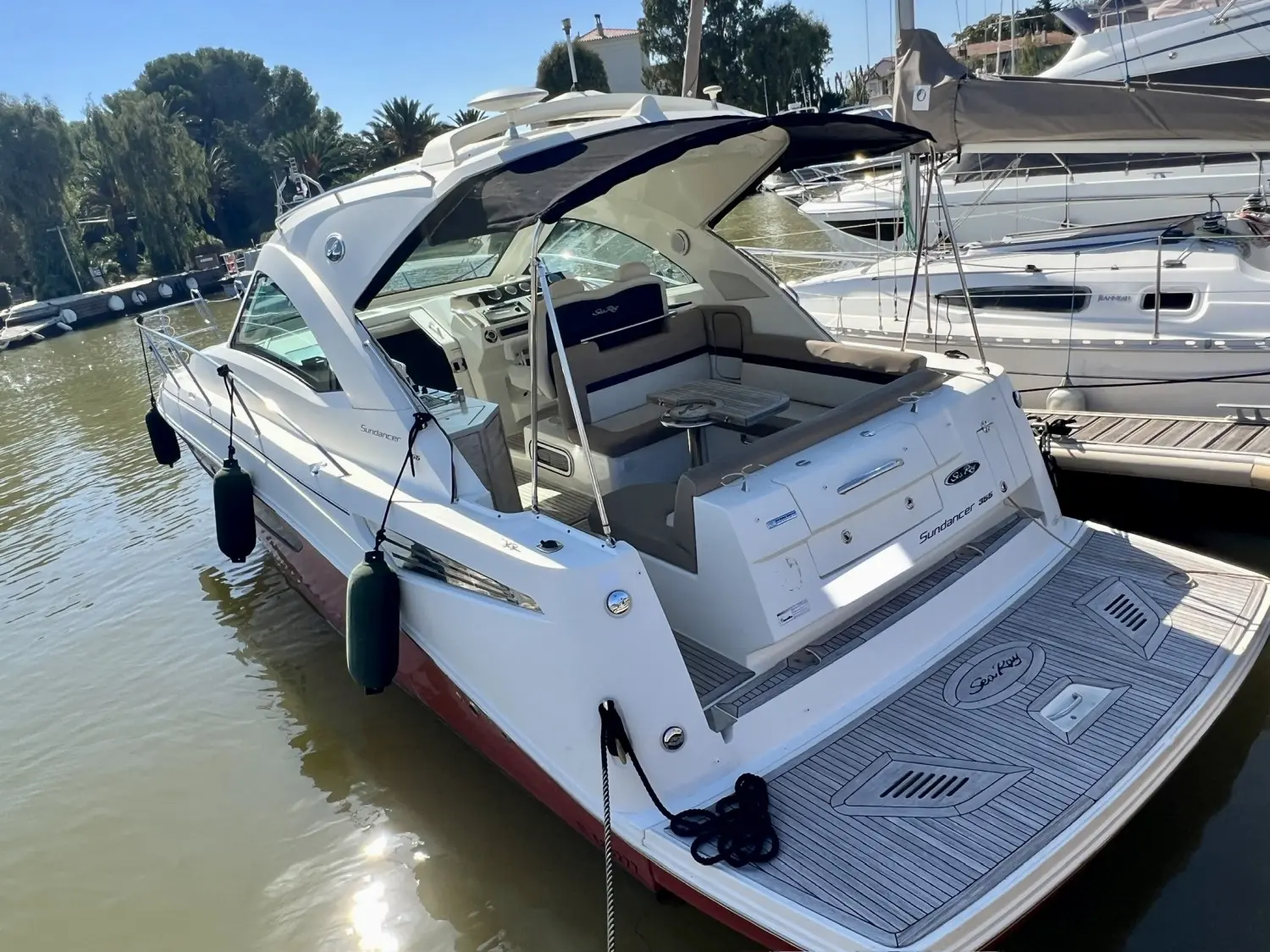 Sea Ray 355 Sundancer — Bateau à moteur blanc vu de trois quarts arrière dans un port de plaisance.