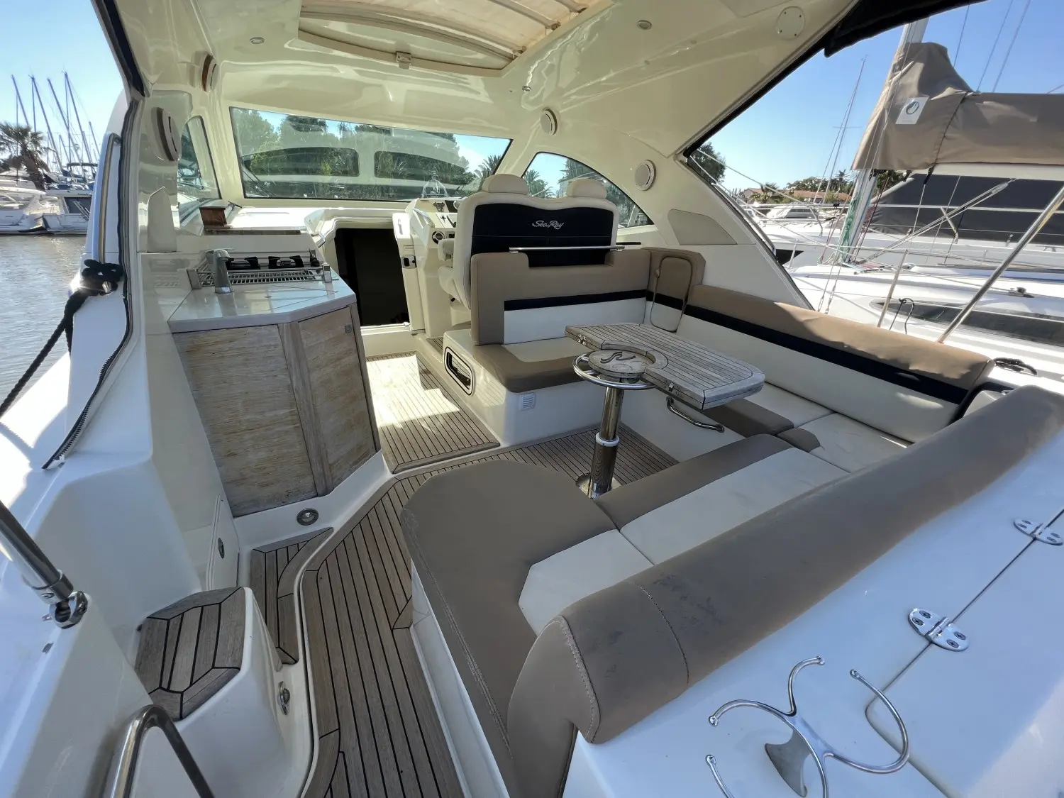 Sea Ray 355 Sundancer — Vue du cockpit avec banquettes, table, poste de pilotage et cuisine extérieure.
