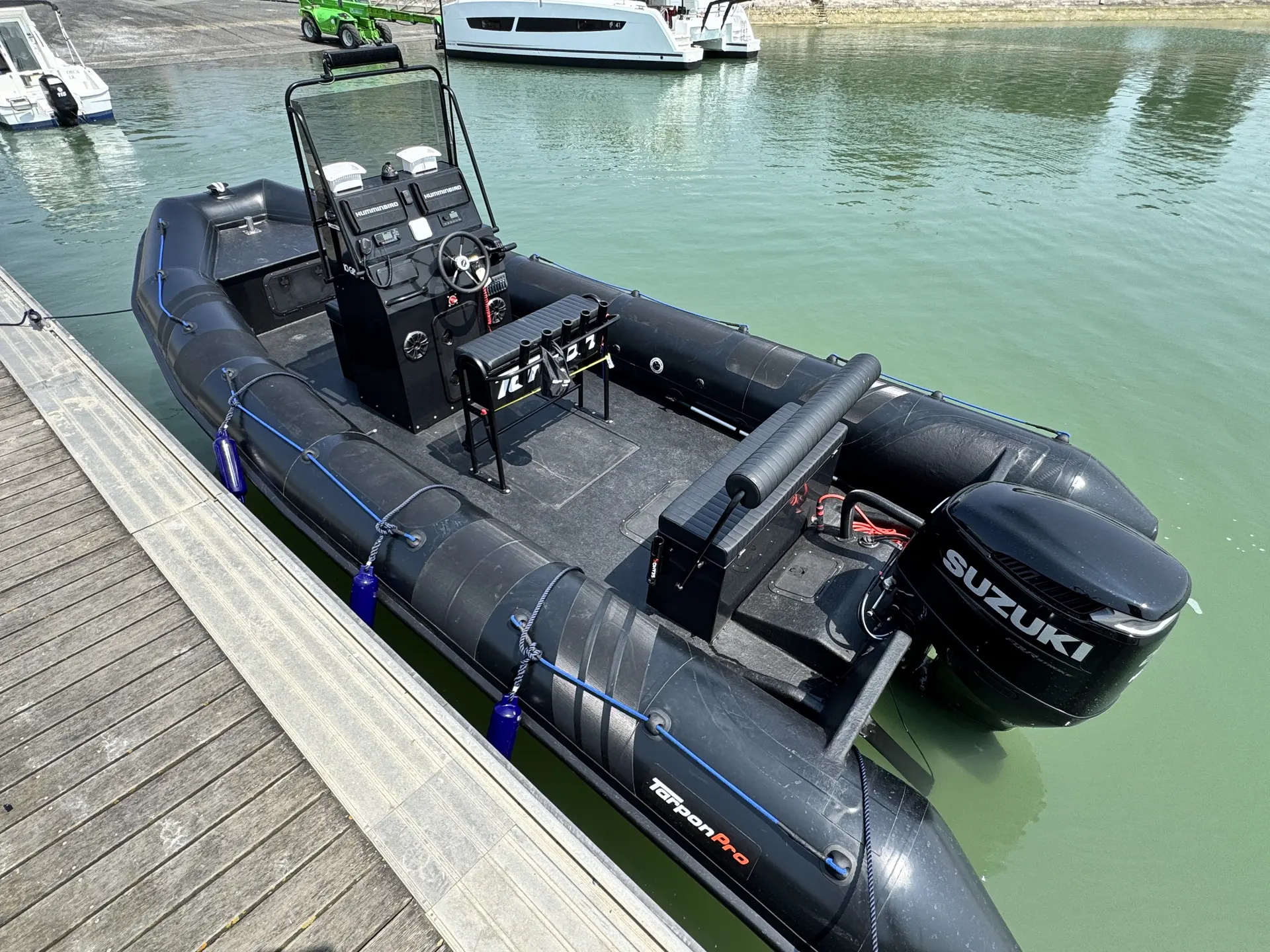 Tarpon DV 70 — Bateau pneumatique noir vu au quai, avec console centrale et moteur hors-bord.