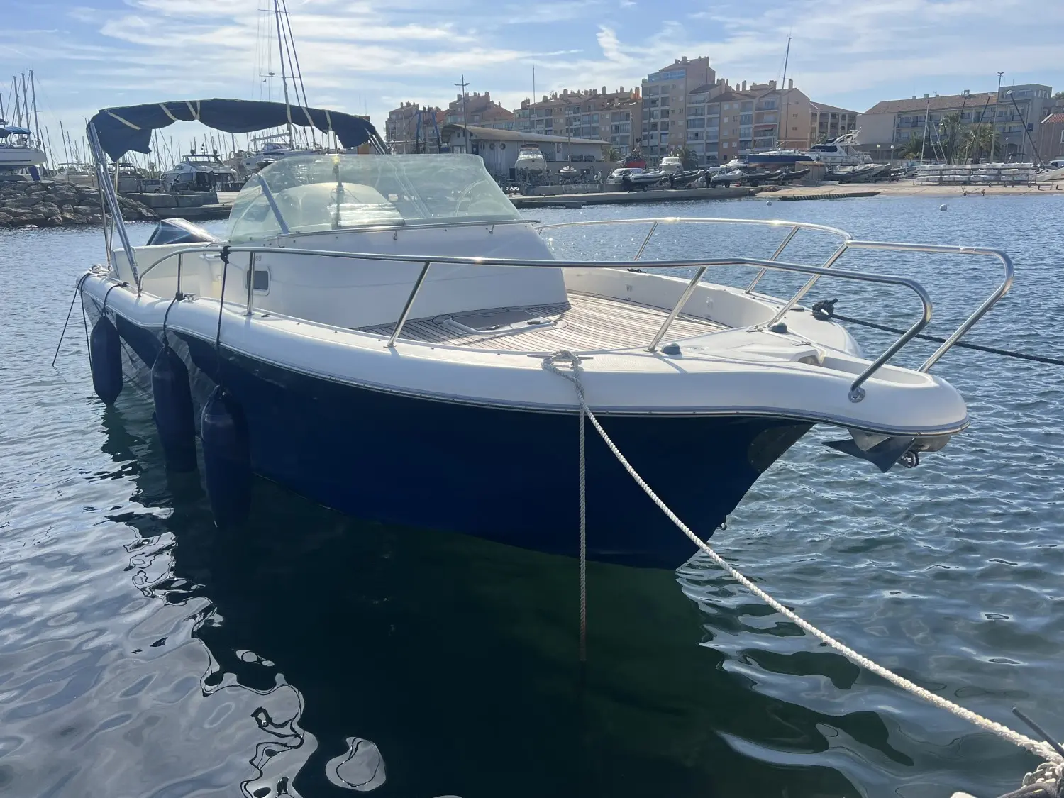 White Shark 268 — Bateau à moteur blanc et bleu amarré dans un port, vu de trois quarts avant.