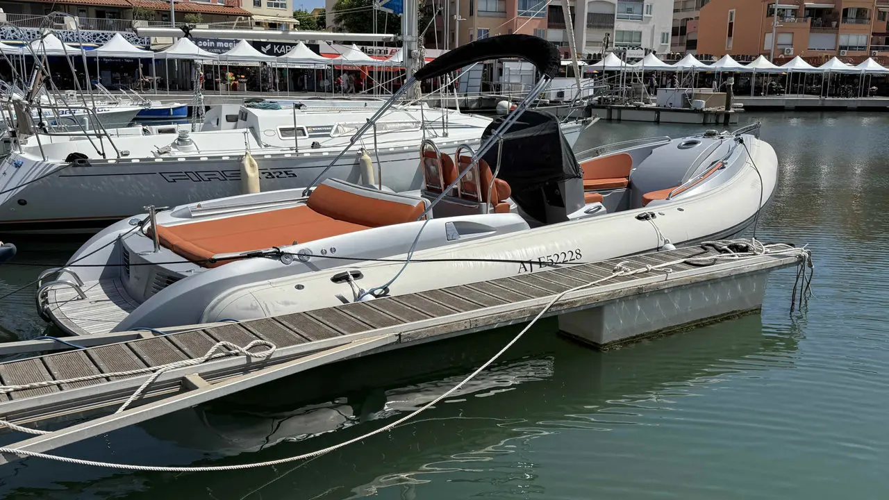 Neptys First Life 27 — Bateau pneumatique blanc à sellerie orange amarré dans un port.