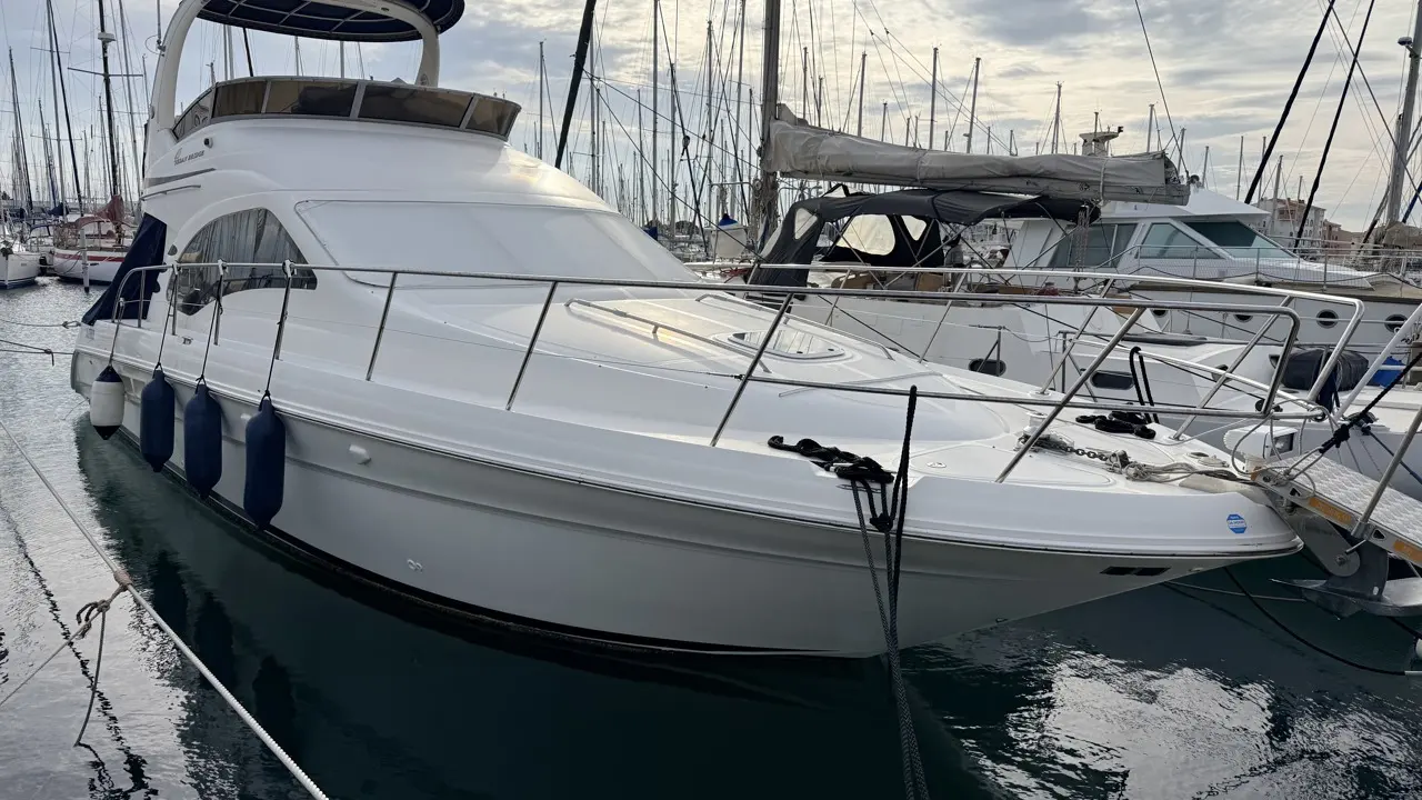 Sea Ray 455 Sedan Bridge — Bateau à moteur blanc amarré dans une marina, vu de trois quarts avant.