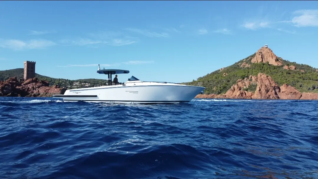 Canados 431 Gladiator — Bateau blanc vu de profil au large d'une côte rocheuse, par mer agitée.