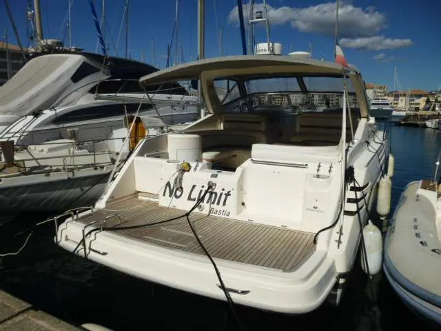 Cranchi Mediterranee 40 — Vue arrière trois-quarts d’un bateau à moteur amarré dans un port.