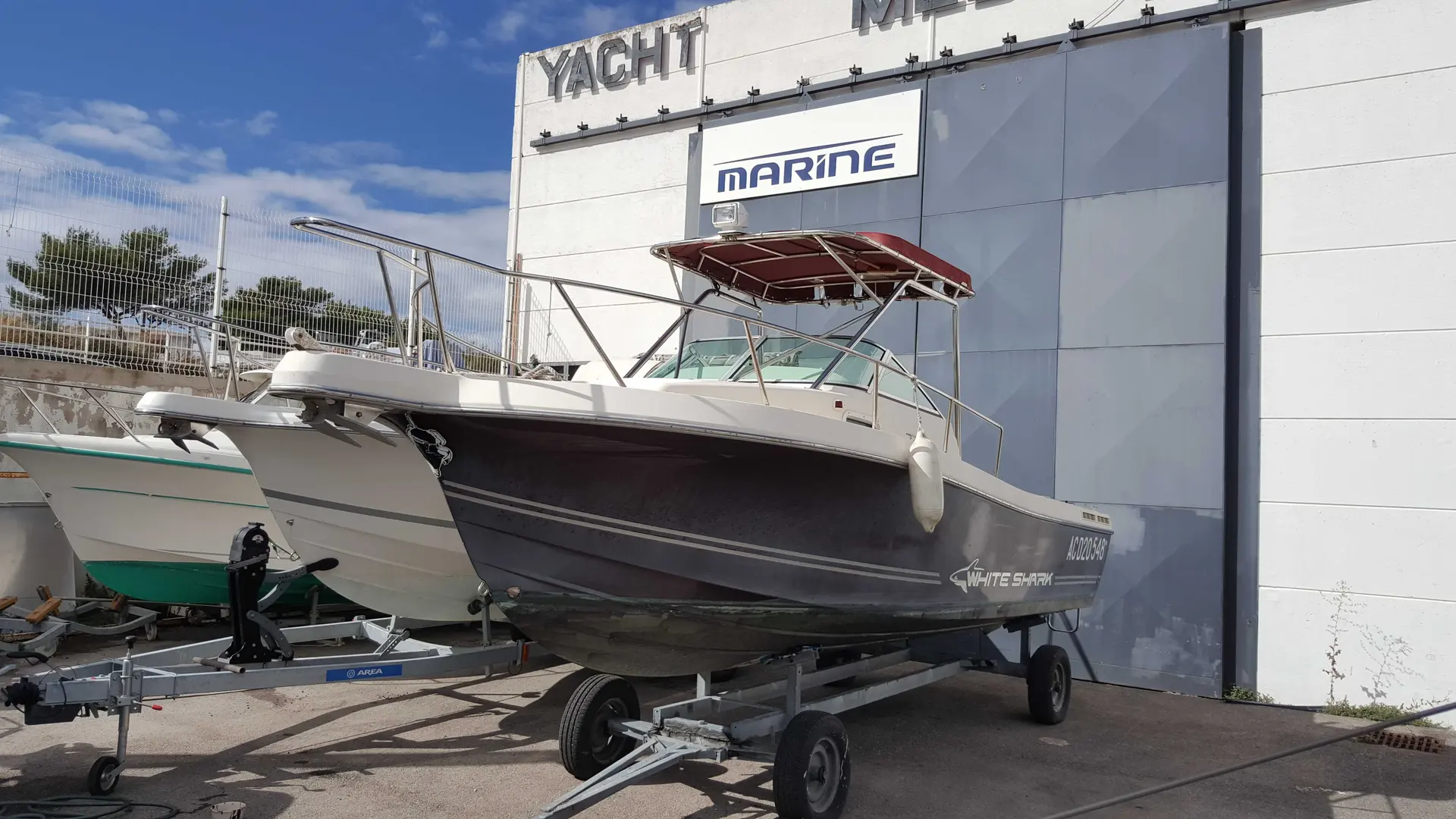 White Shark 237 — Bateau à moteur blanc et noir présenté sur remorque devant un bâtiment nautique.
