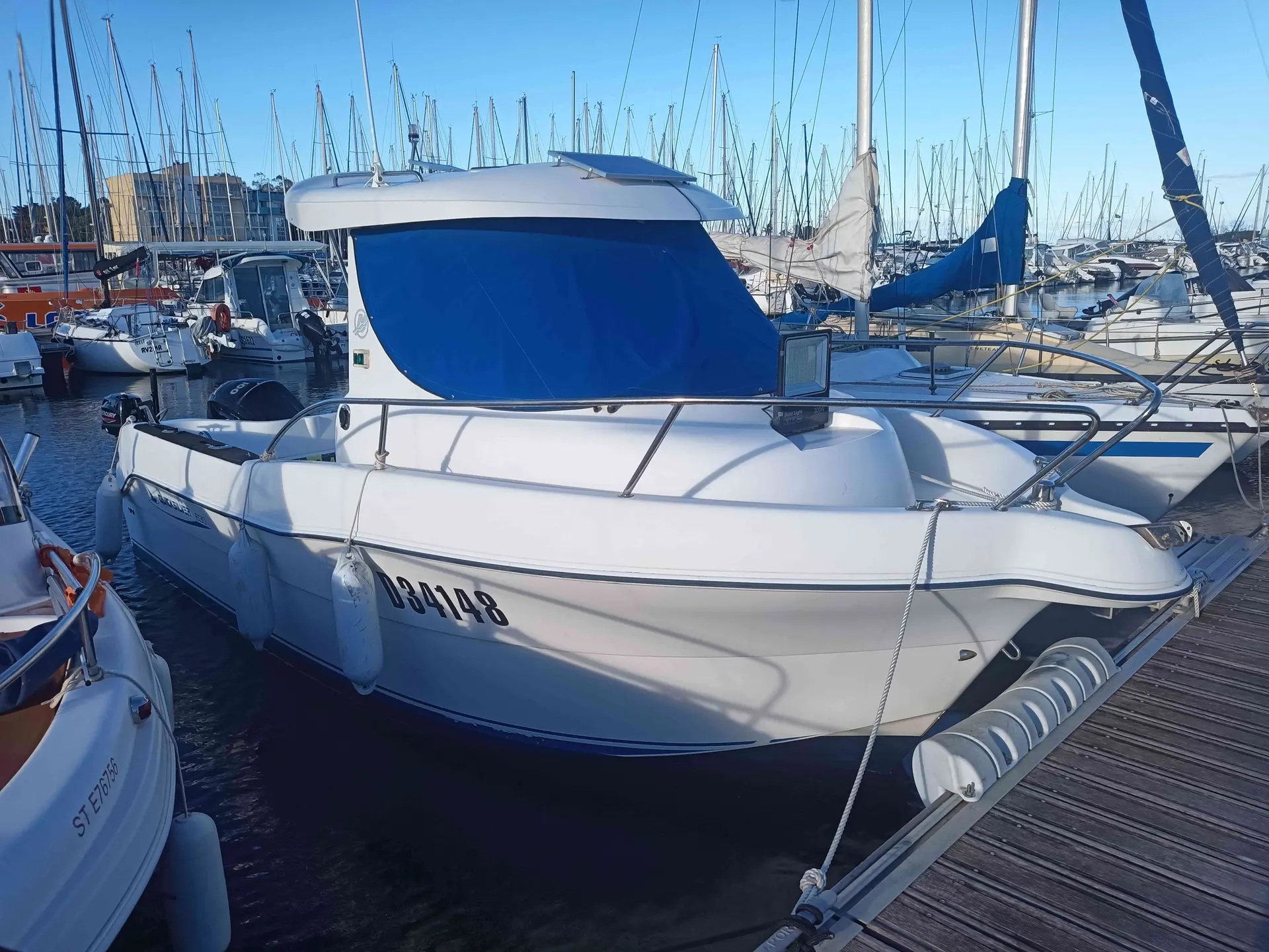Quicksilver 630 Open — Vedette blanche amarrée dans un port, vue de trois quarts avant.