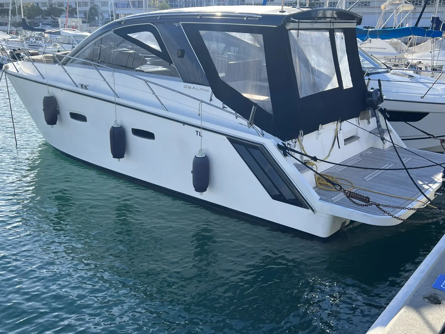 Sealine SC 35 — Bateau à moteur blanc amarré dans une marina, vu de trois quarts.