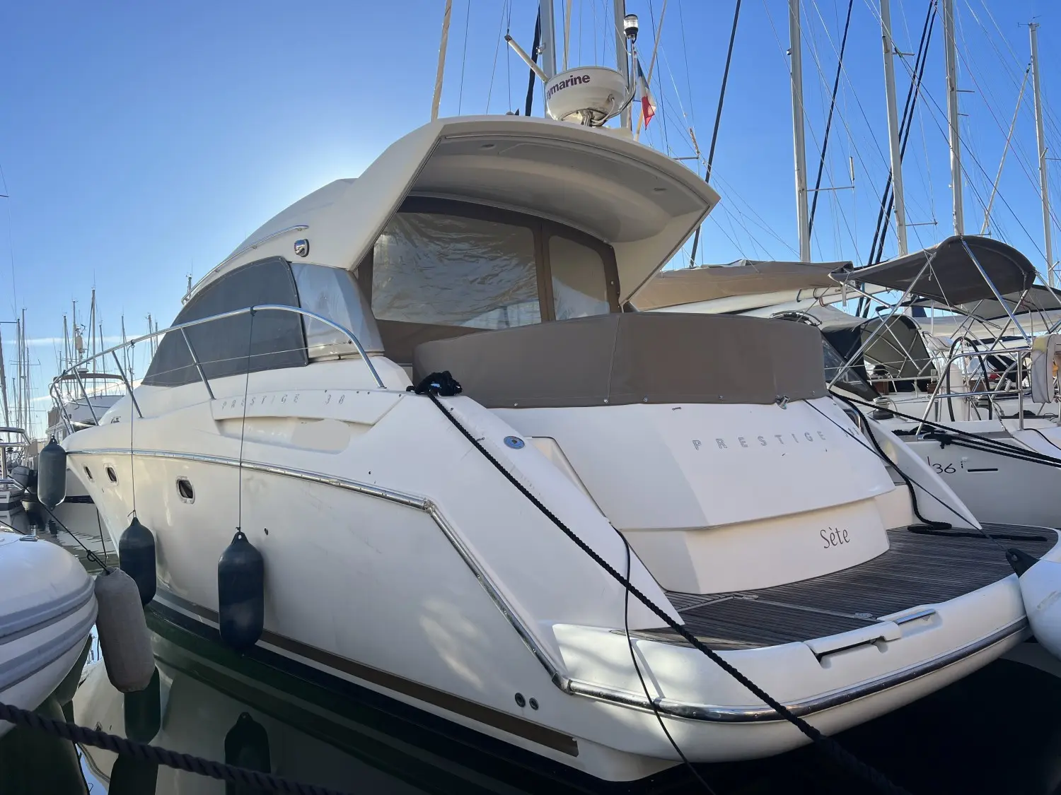 Jeanneau Prestige 38 — Vue arrière trois-quarts d’un bateau à moteur blanc amarré dans un port.