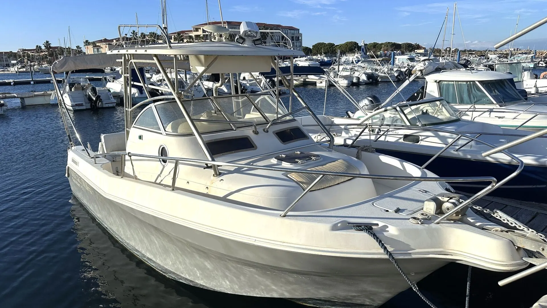 Quicksilver 750 WA Commander — Bateau à moteur blanc amarré dans une marina, vu de trois quarts avant.