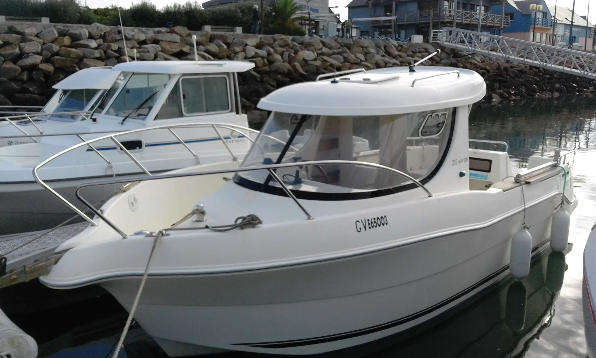 Arvor 215 — Bateau blanc à cabine amarré dans un port, vu de trois quarts avant.