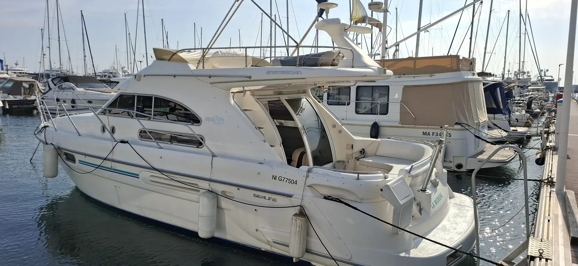 Sealine 360 — Bateau à moteur blanc amarré dans une marina, vu de trois quarts arrière.