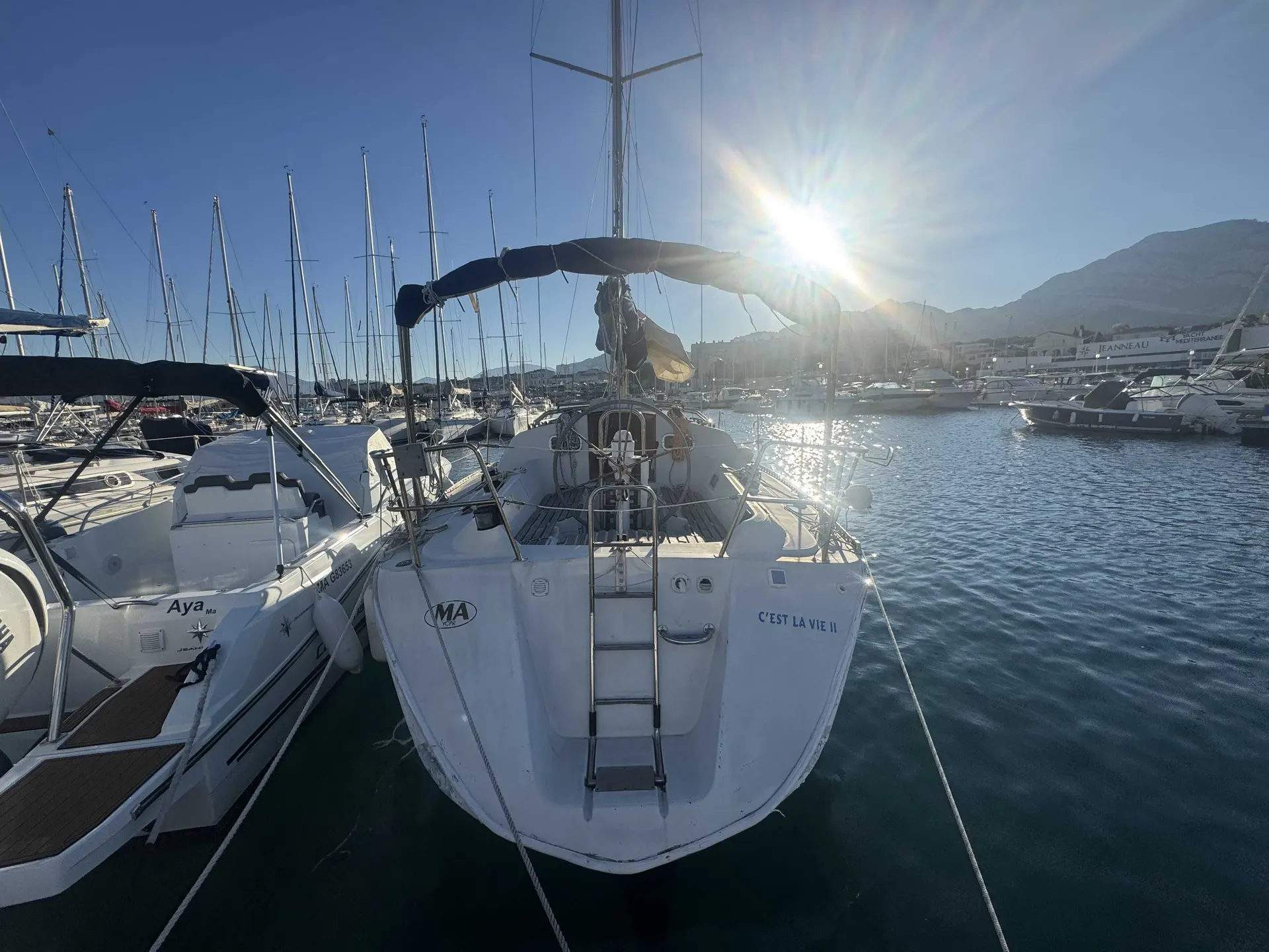 Kirie Feeling 346 — Vue arrière d’un voilier amarré dans un port, entouré d’autres bateaux.