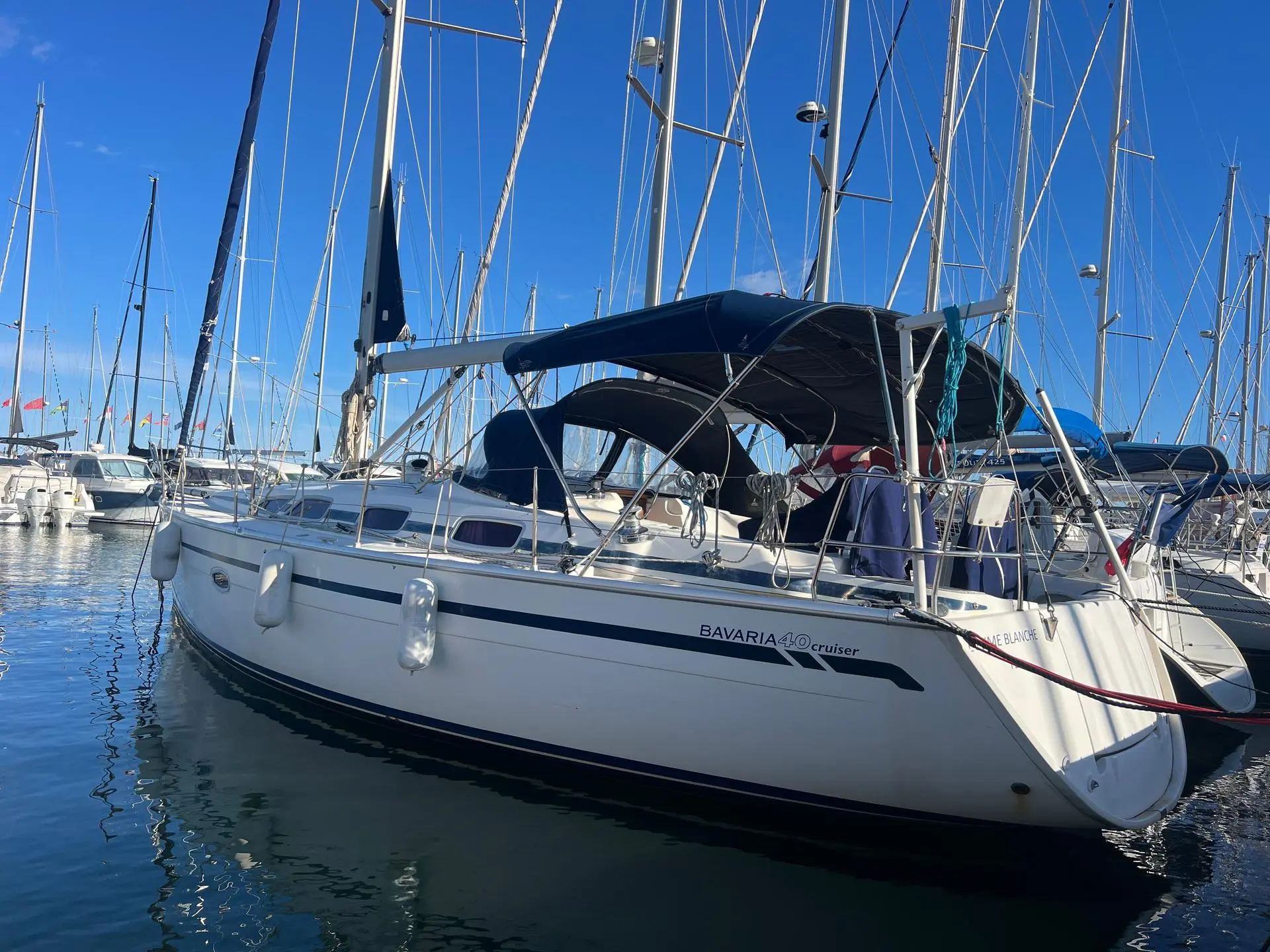 Bavaria 40 — Voilier blanc amarré dans un port de plaisance, vu de trois quarts arrière.