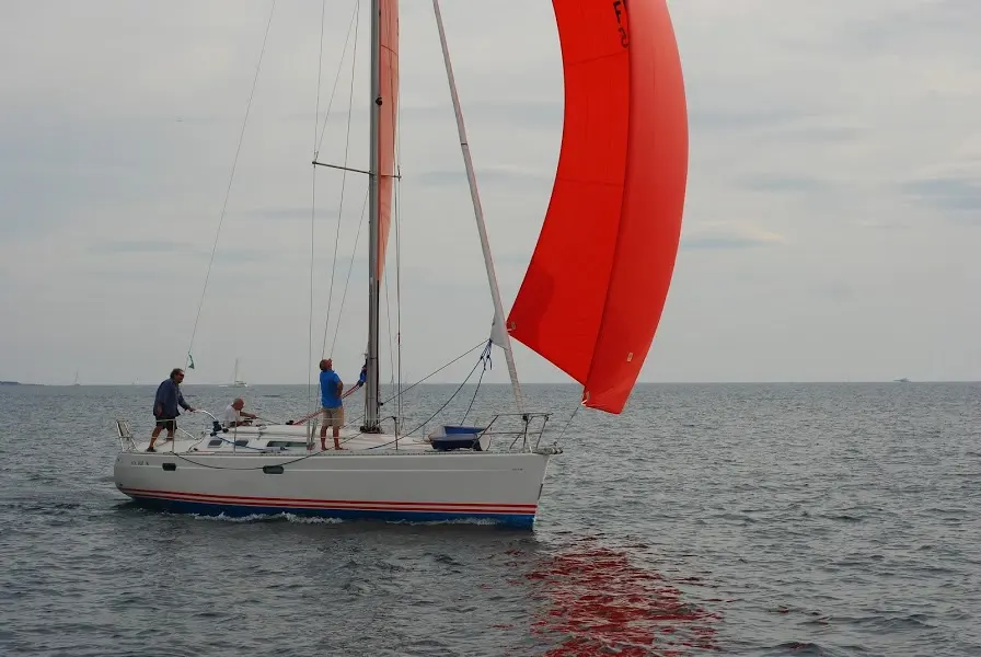 Jeanneau Sun Fast 36 — Voilier blanc naviguant sous voile rouge par temps couvert.