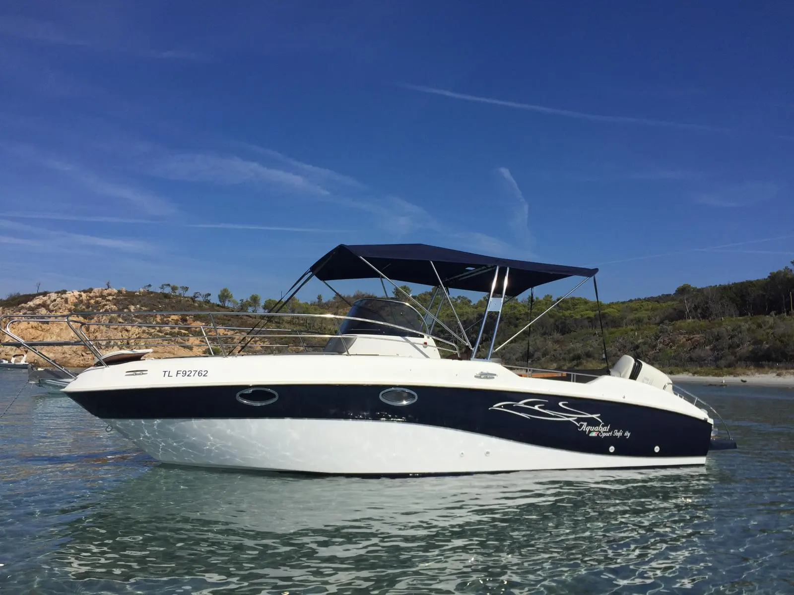 Aquabat Sport Infinity 750 — Bateau à moteur vu de profil sur l’eau, avec taud de soleil déployé.