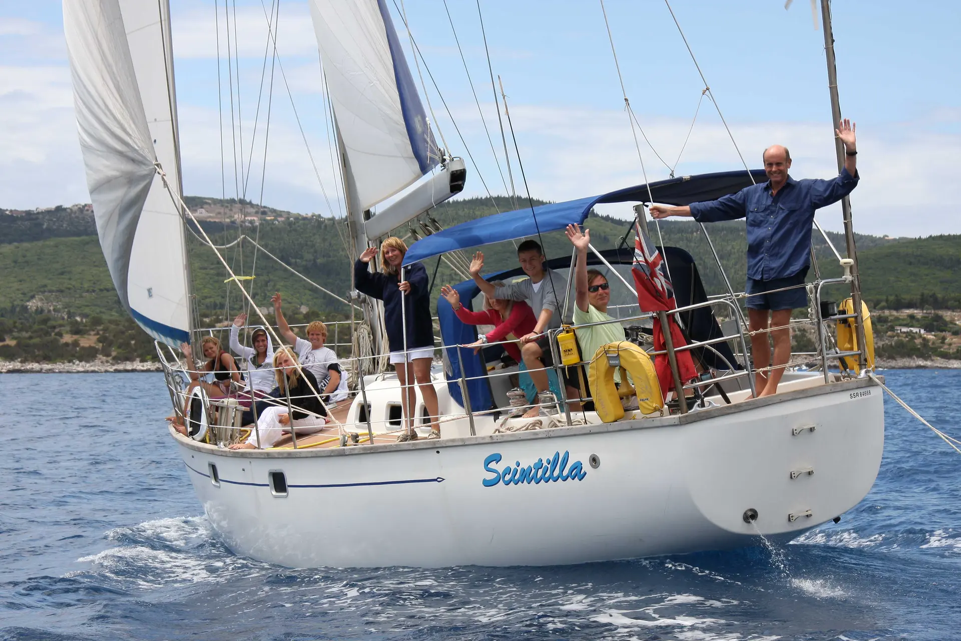 Bruce Roberts 45 Spray — Voilier blanc photographié de trois quarts bâbord, sous voiles, avec plusieurs personnes à bord.