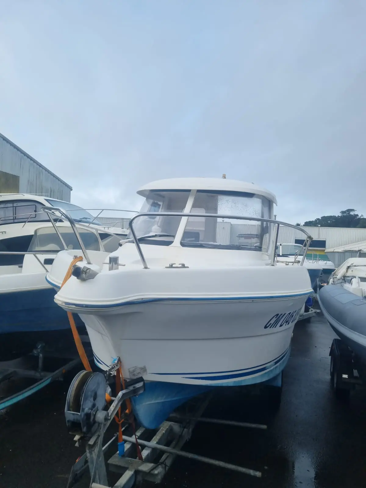 Quicksilver 640 Pilothouse — Bateau à cabine photographié de face sur une remorque, entre d’autres bateaux.