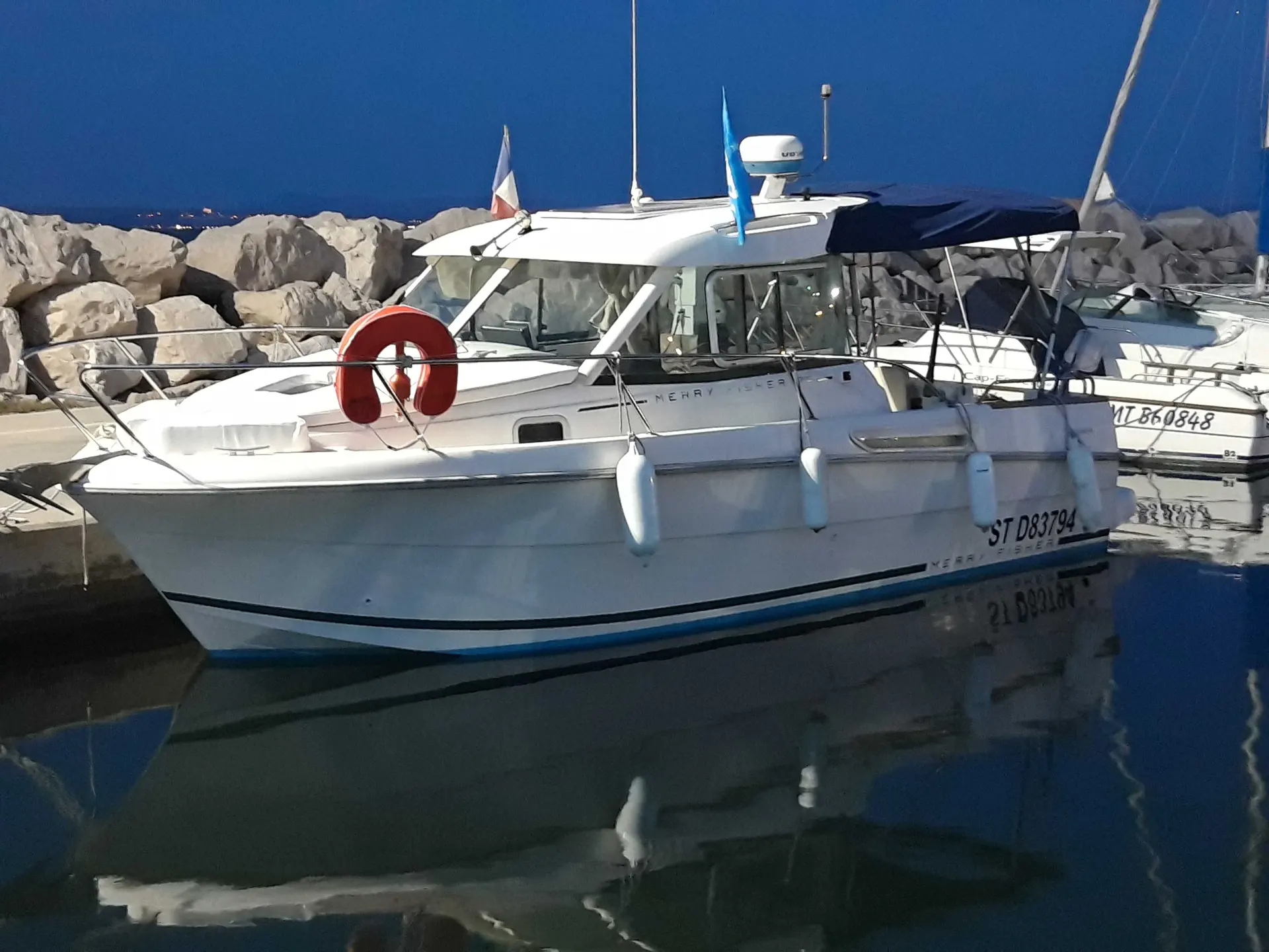 Jeanneau Merry Fisher 705 — Bateau à moteur blanc amarré dans un port au crépuscule.