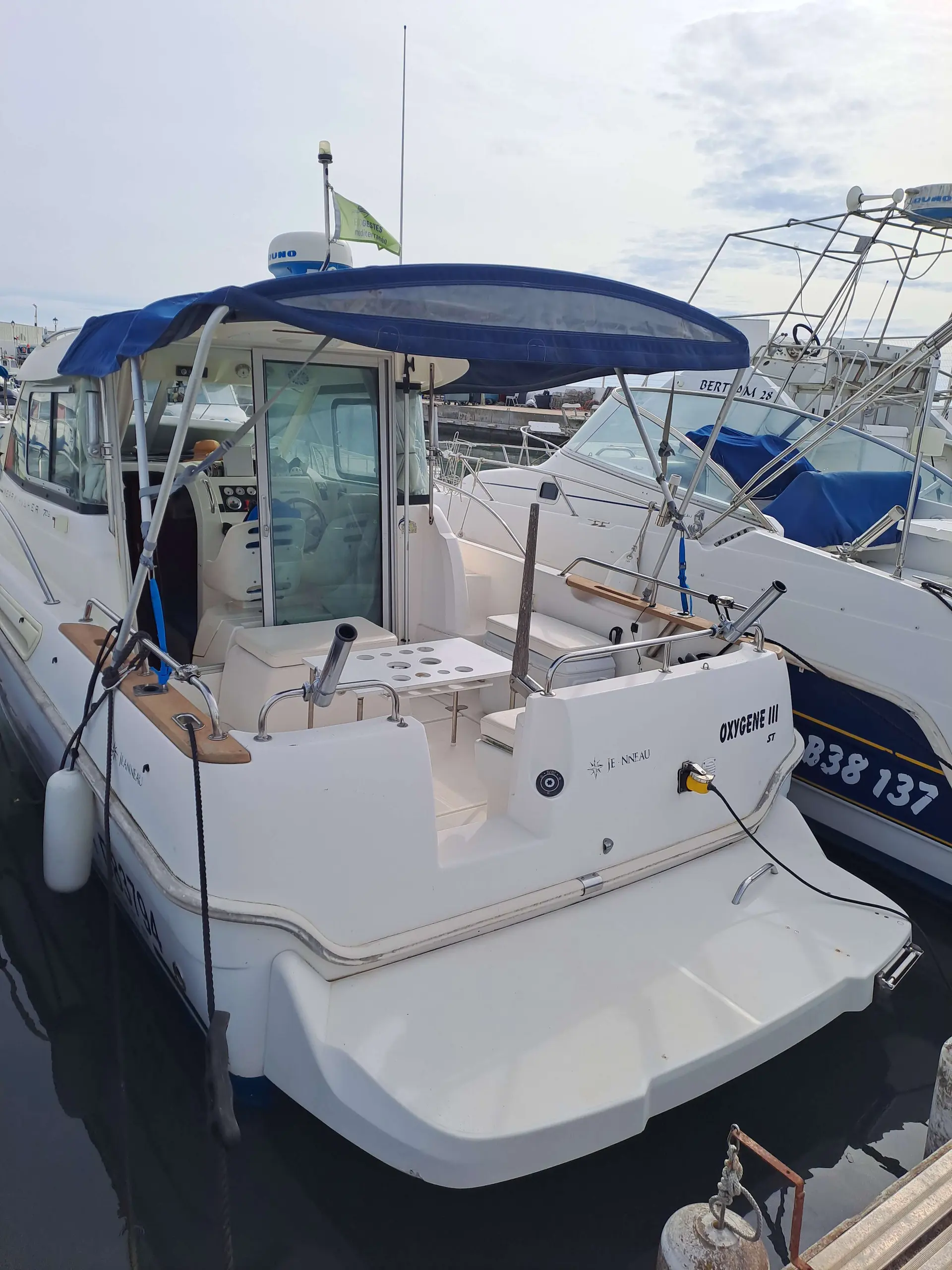 Jeanneau Merry Fisher 705 — Vue arrière d’un bateau à moteur amarré, avec cockpit et plateforme de bain visibles.