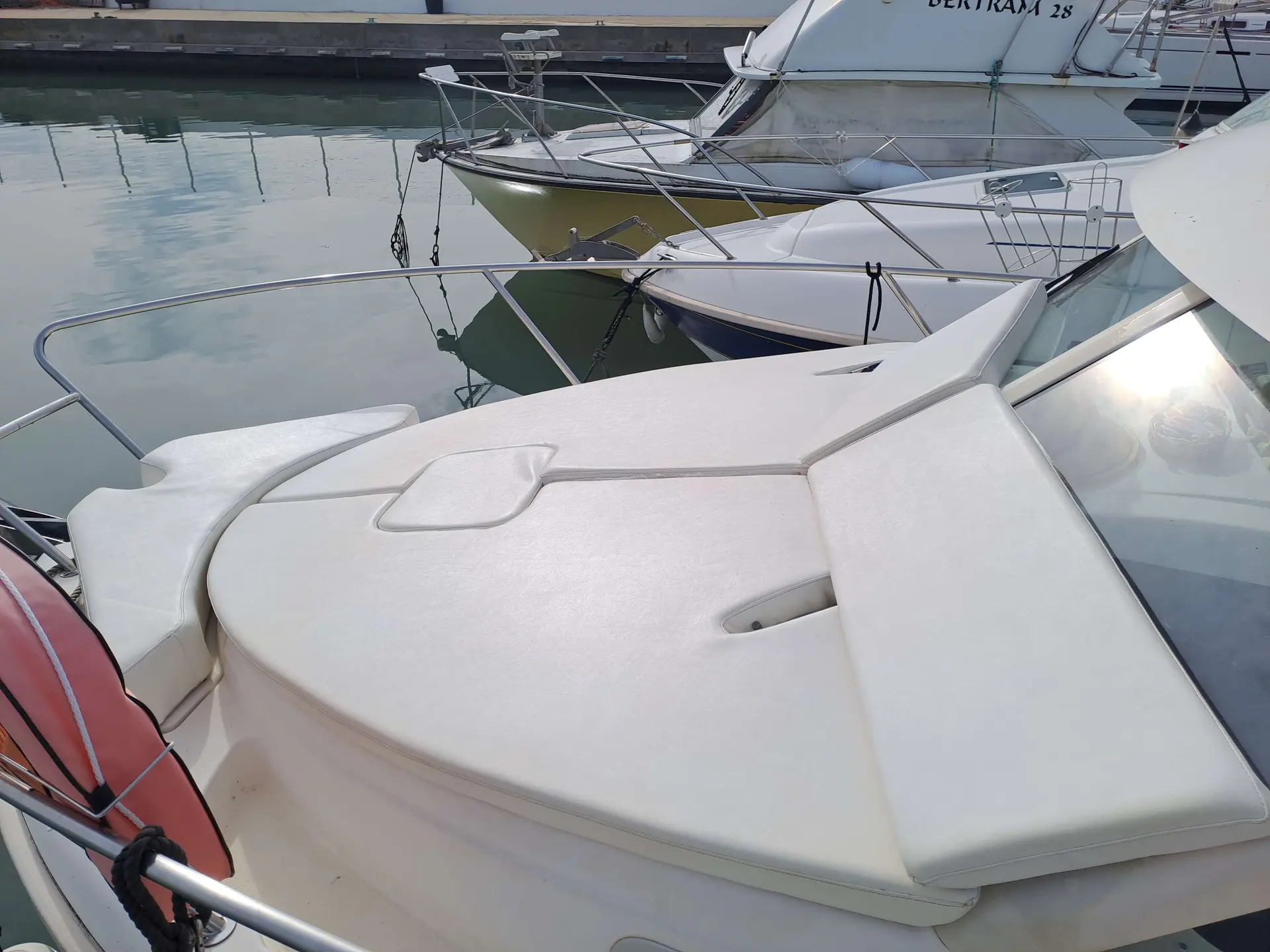 Jeanneau Merry Fisher 705 — Vue rapprochée d'un bain de soleil blanc à l'avant d'un bateau amarré.