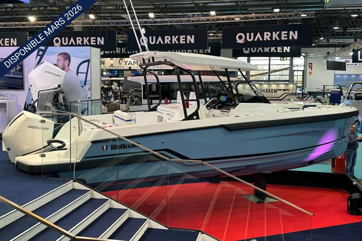 Wellcraft 28 T-Top — Bateau exposé dans un salon nautique, vu de profil avec son moteur hors-bord.