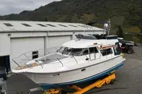 Storebro 410 Commander — Bateau à moteur blanc et bleu stationné sur une remorque devant un hangar.