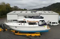Storebro 410 Commander — Bateau à moteur blanc vu de trois quarts, stationné sur un terre-plein.