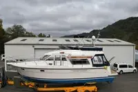 Storebro 410 Commander — Bateau à moteur blanc et bleu photographié à terre devant un bâtiment.