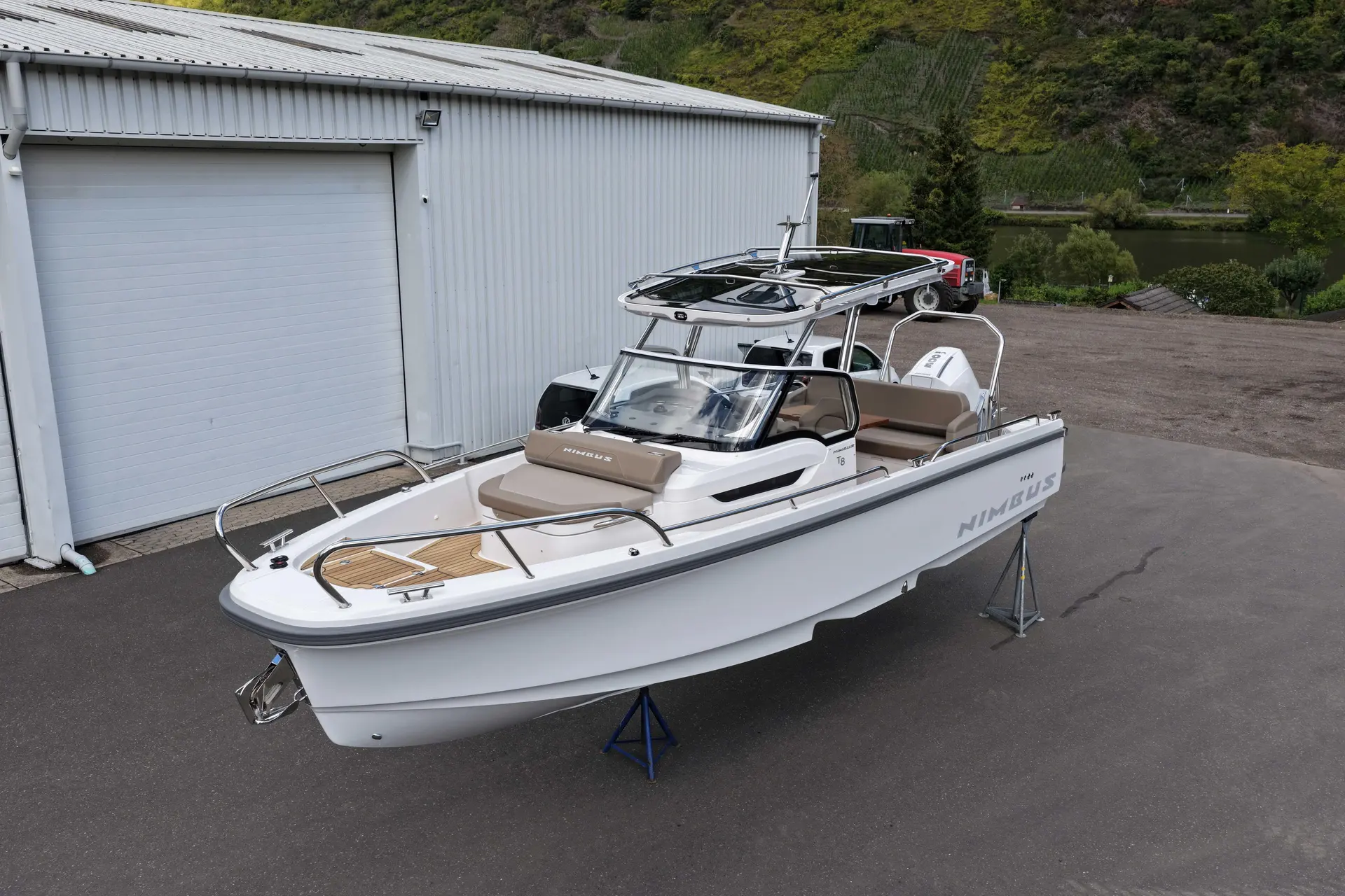 Nimbus T8 — Bateau blanc à console centrale photographié à terre devant un hangar.