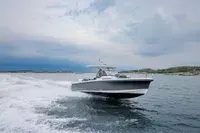 Nimbus T8 — Bateau à moteur naviguant au large, avec une traînée d’écume et un littoral en arrière-plan.