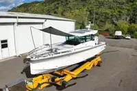 Axopar 29 XC CROSS CABIN — Bateau blanc posé sur une remorque, photographié à terre devant un bâtiment.