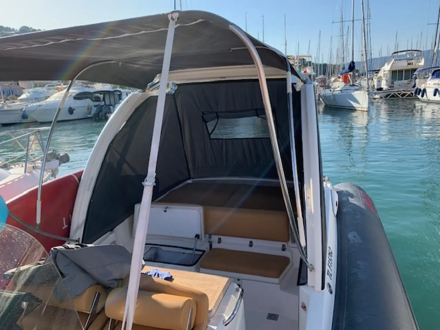 Joker Boat Mainstream 33 — Vue arrière d’un bateau semi-rigide amarré, avec taud installé dans un port.