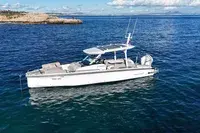 Axopar 29 Sun Top — Vue aérienne de trois quarts d’un bateau blanc naviguant en mer.