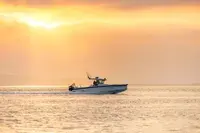 Axopar 29 CCX — Bateau à moteur vu de profil sur une mer calme au coucher du soleil.