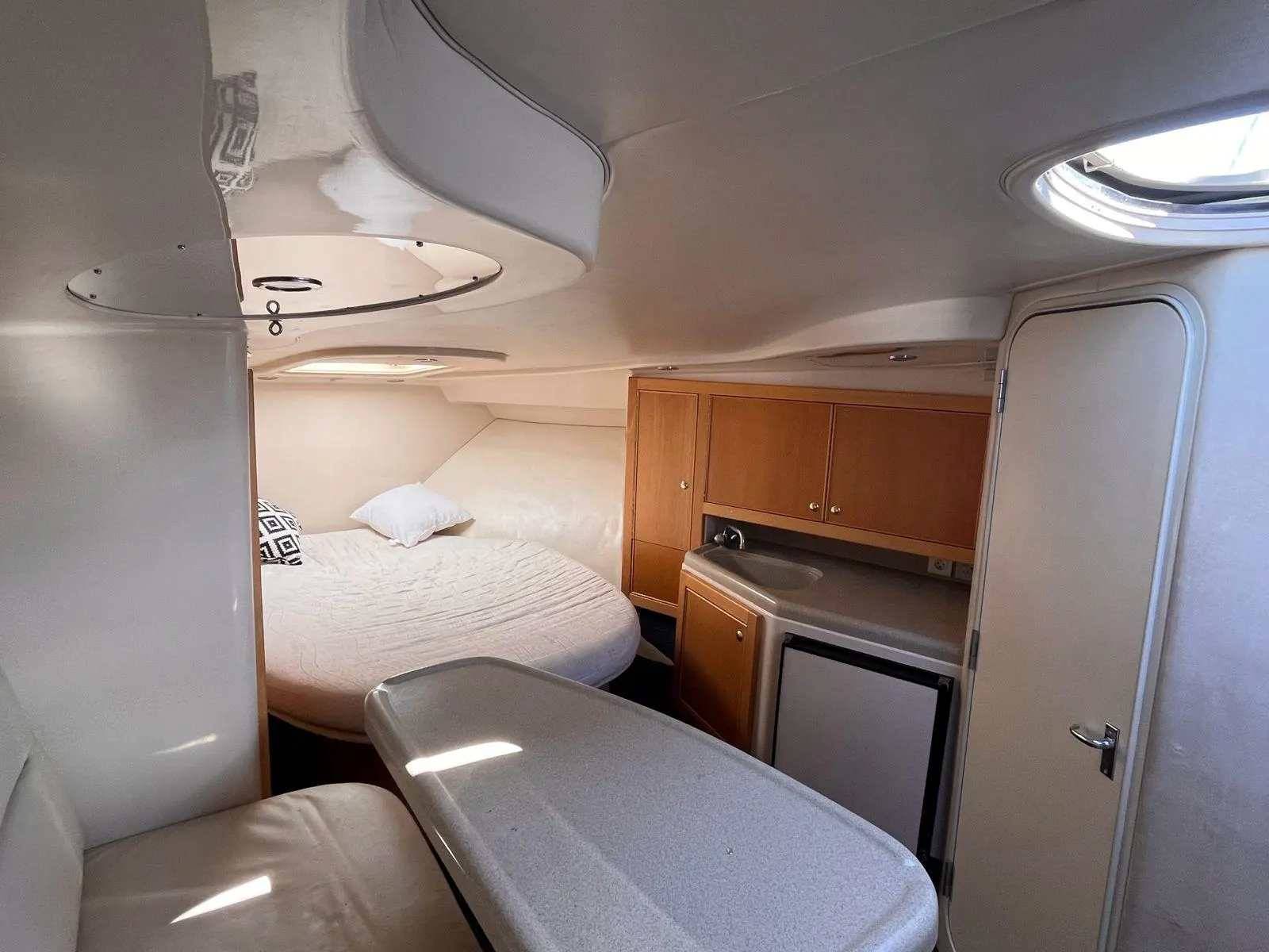 Riviera 3000 — Cabine avant avec couchette double, rangements en bois et réfrigérateur.