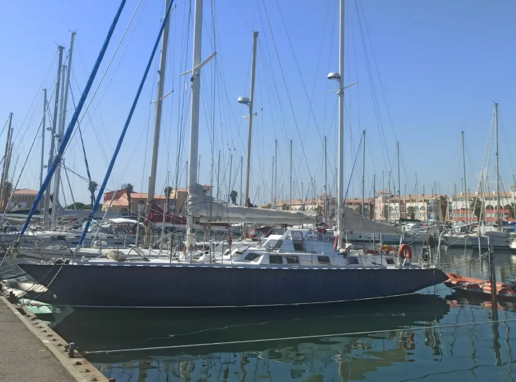 Destrier Sagien 56 — Voilier à coque sombre amarré dans un port de plaisance.