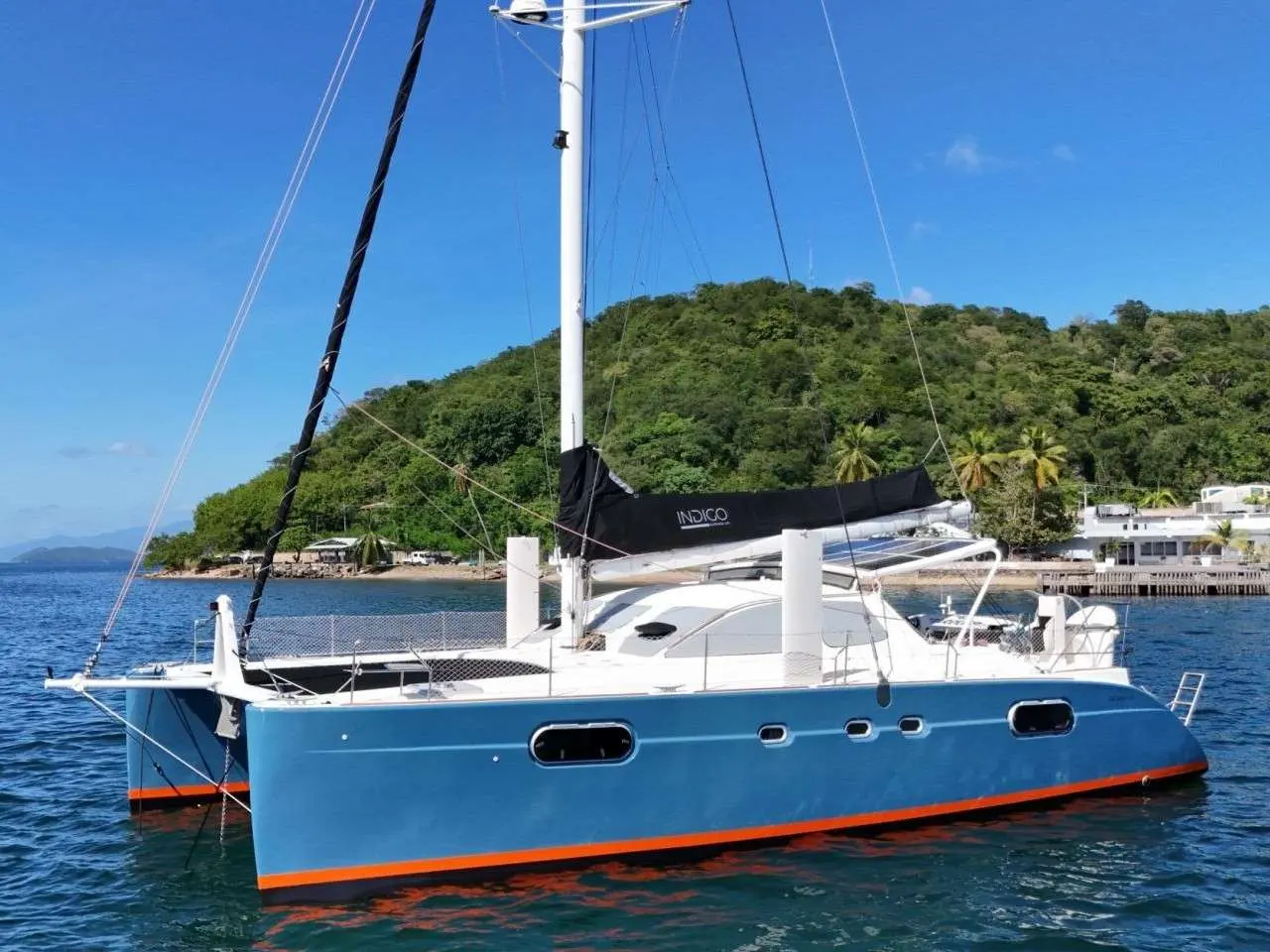 Catana 471 — Catamaran bleu et blanc au mouillage devant une île tropicale.
