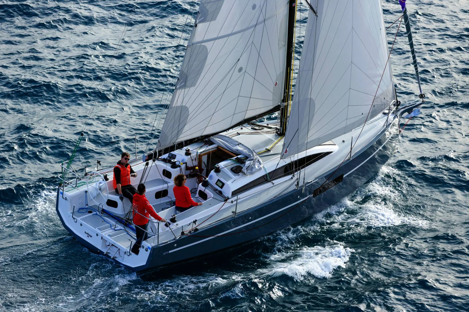 RM Yachts RM 970 — Voilier blanc naviguant à la voile, vu de trois quarts arrière en mer.
