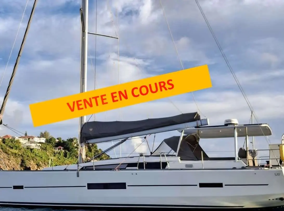Dufour 520 Grand Large — Voilier vu de profil, amarré, avec une bannière « VENTE EN COURS » superposée.