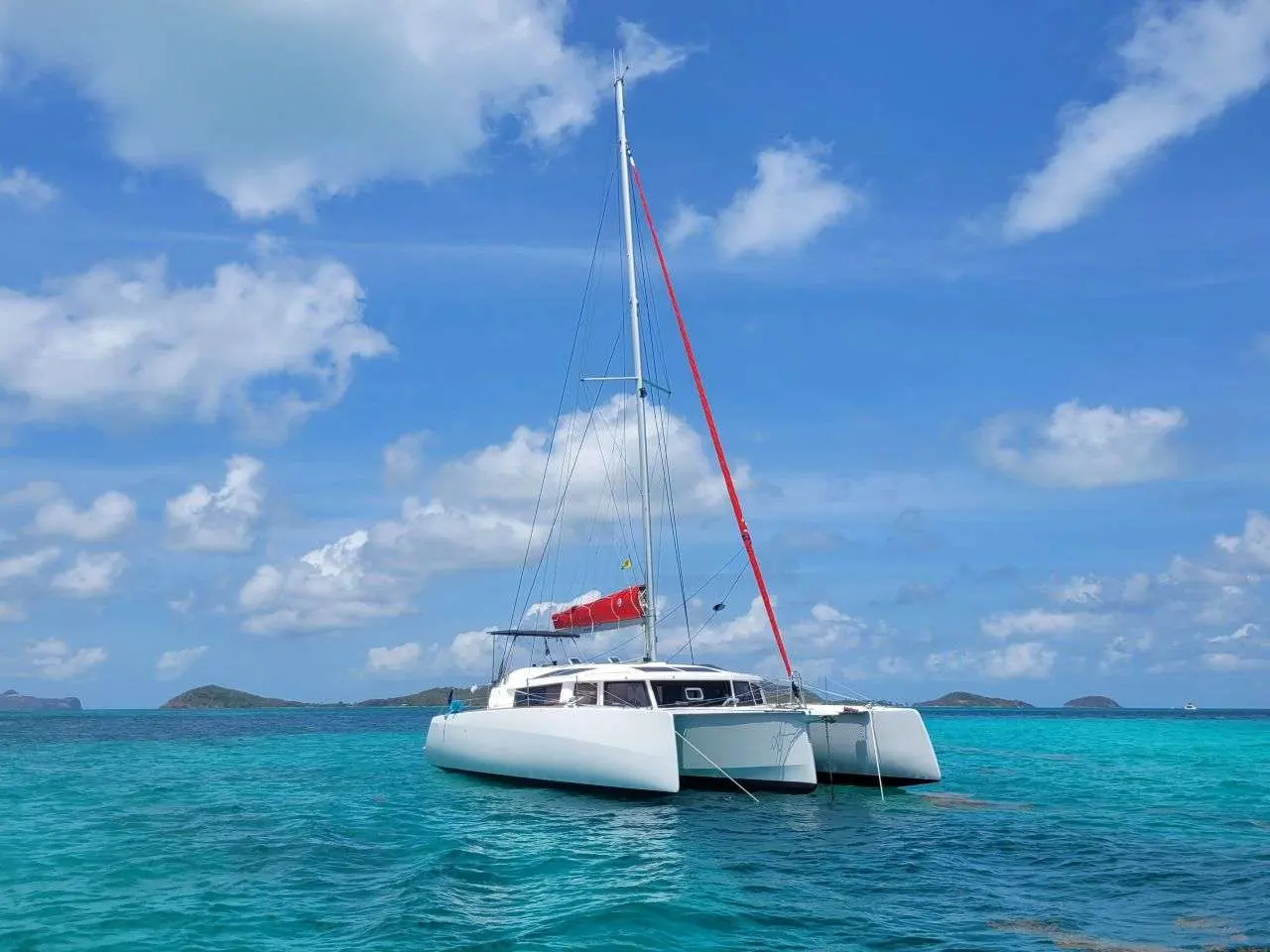 Neel Trimarans Neel 43 — Trimaran blanc au mouillage dans une baie aux eaux turquoise.