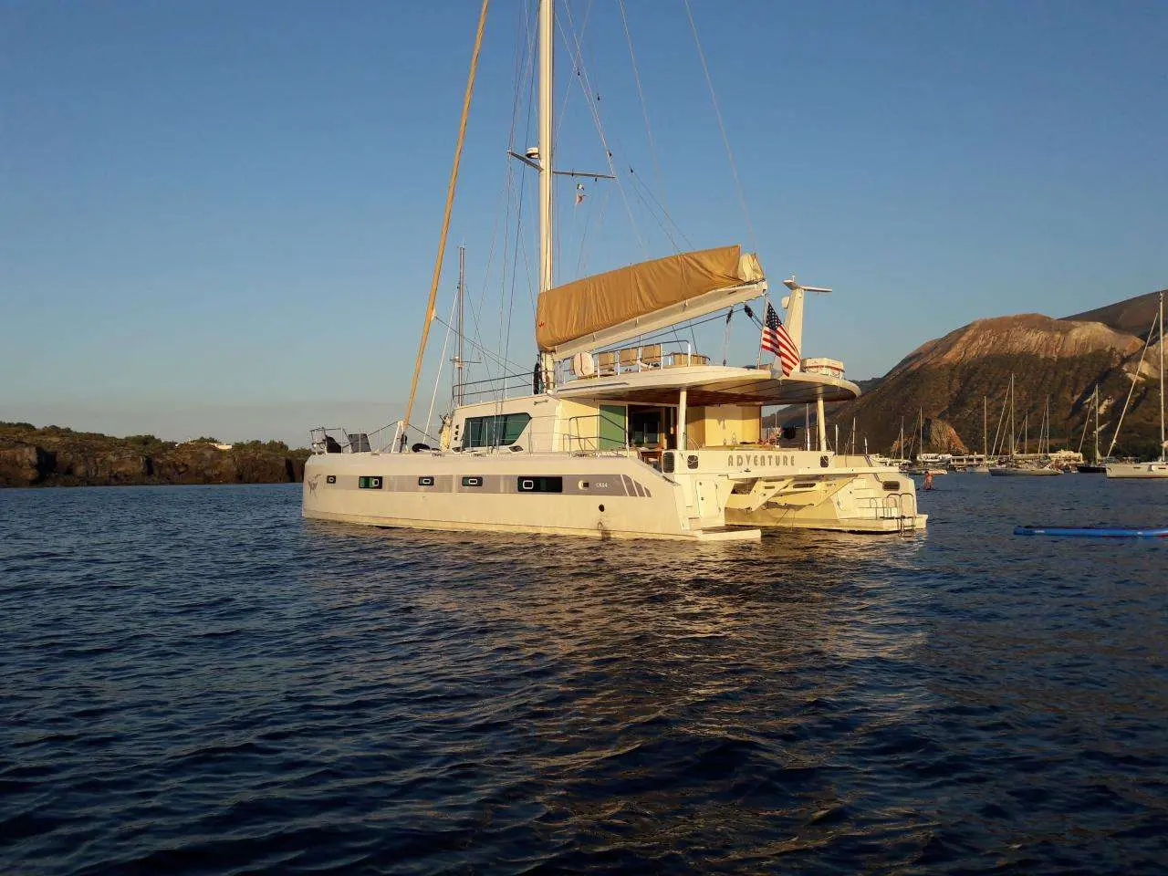 Squalt Marine International CK64 — Catamaran à voile photographié au mouillage dans une baie montagneuse.