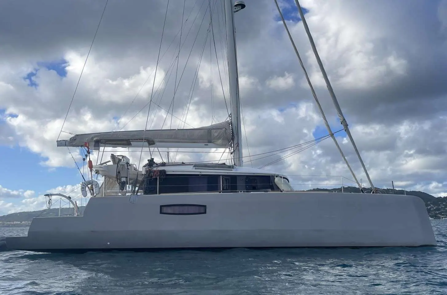 Neel Trimarans Neel 51 — Trimaran blanc photographié de profil sur l’eau, sous un ciel nuageux.