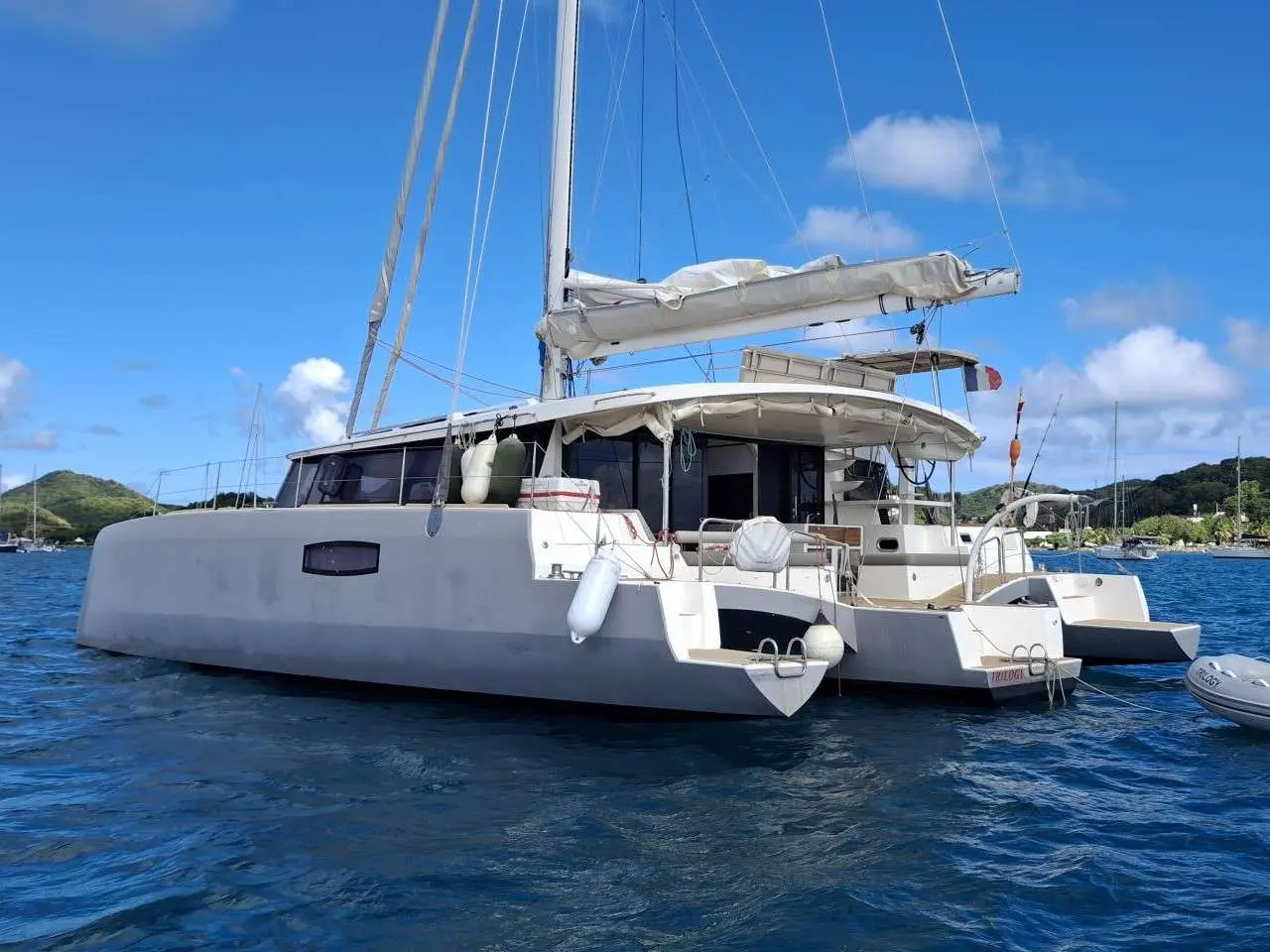 Neel Trimarans Neel 51 — Trimaran blanc vu de trois quarts sur une mer calme, avec son annexe à droite.