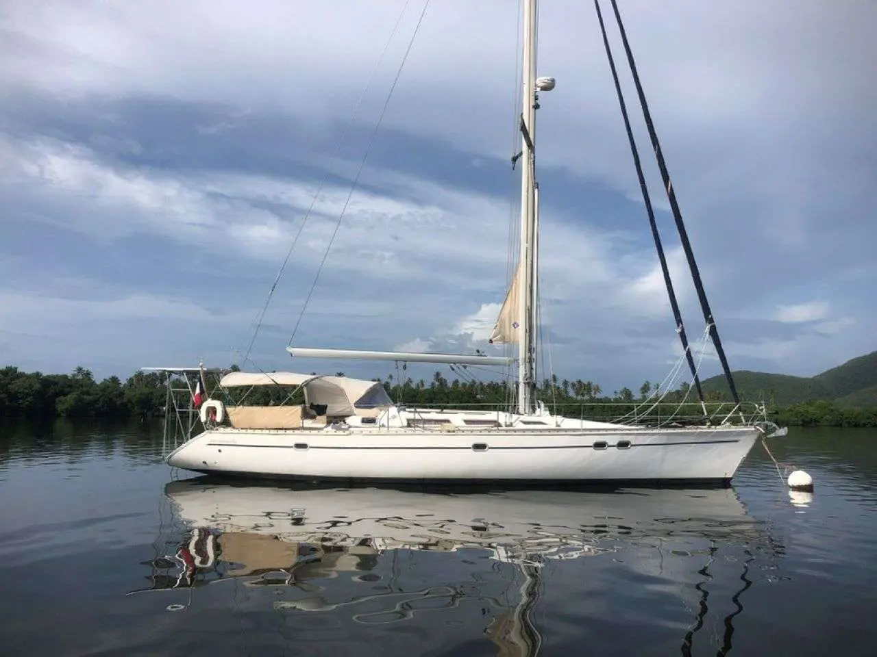 Jeanneau Sun Odyssey 51 — Voilier blanc vu de profil, au mouillage dans une baie tropicale.